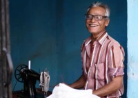 Elderly man using a sewing machine and using glasses